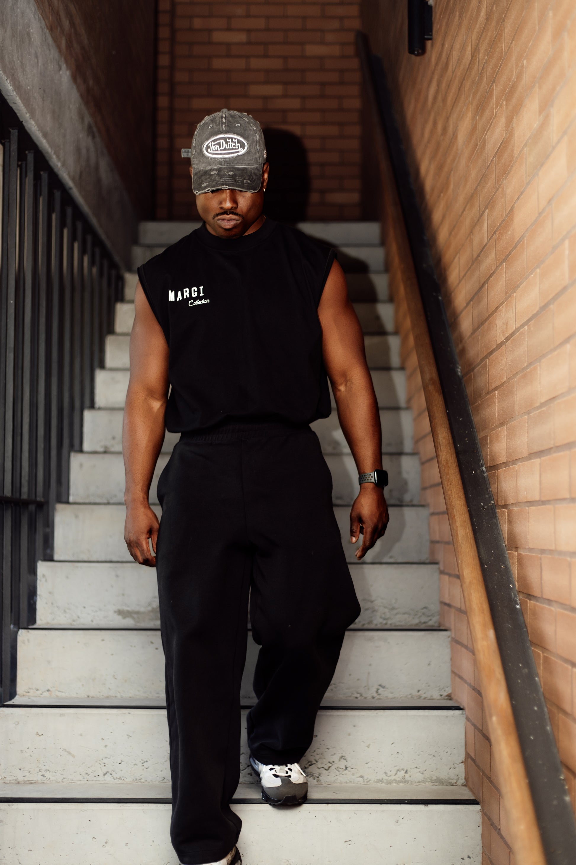 Person wearing a black sleeveless shirt and pants walking down a set of stairs.