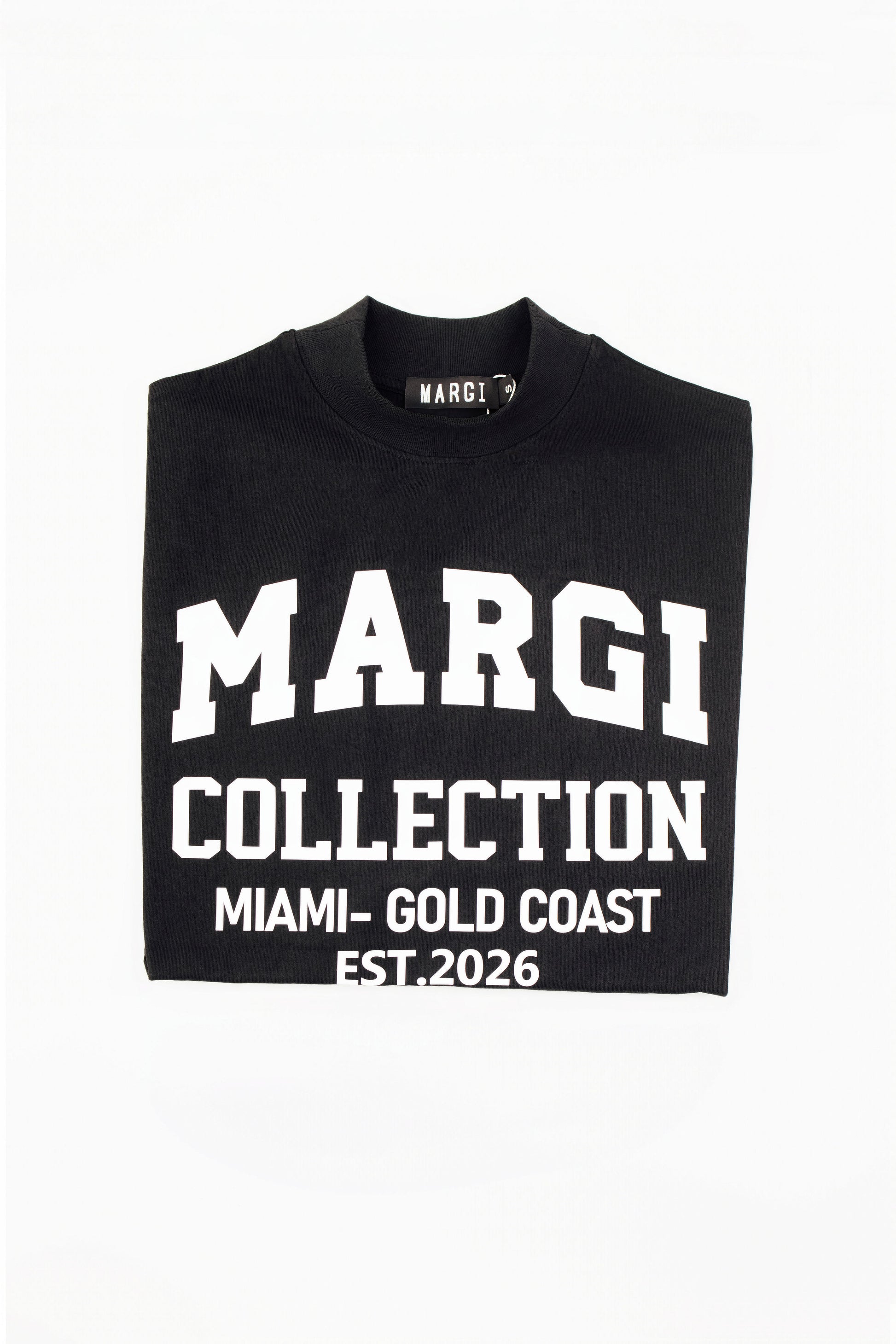 A folded black t-shirt with bold white text reading 'MARGI COLLECTION', 'MIAMI - GOLD COAST', and 'EST. 2026' on a plain white background.