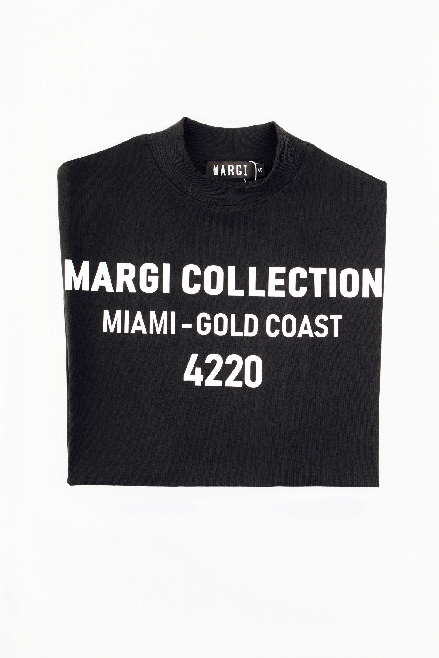 A folded black t-shirt with bold white text reading 'MARGI COLLECTION MIAMI-GOLD COAST 4220' on the front, displayed against a plain white background.
