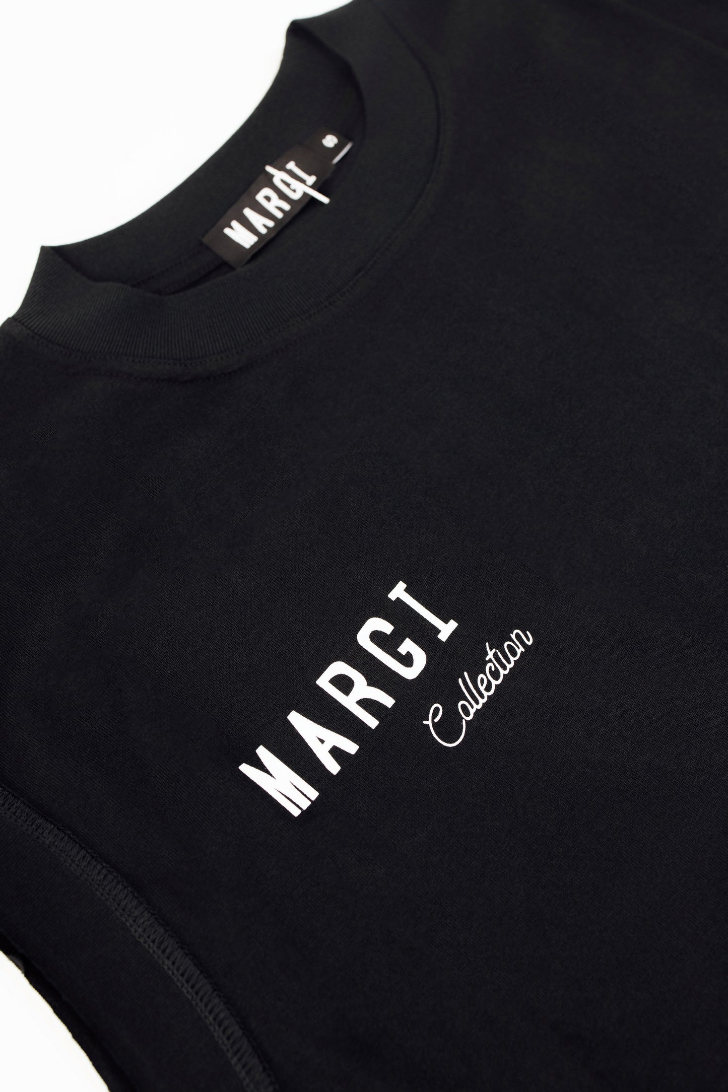 Close-up of a black crewneck sweatshirt featuring white printed 'MARGI Collection' branding on the chest and a matching neck label.